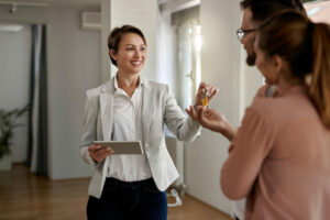 young-happy-real-estate-agent-giving-house-keys-couple-who-is-buying-new-home-980x653